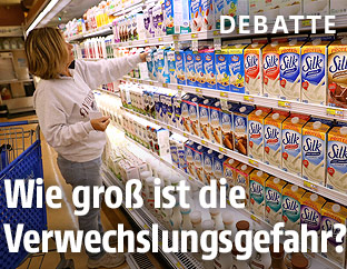Eine Frau steht vor dem Milchregal im Supermarkt