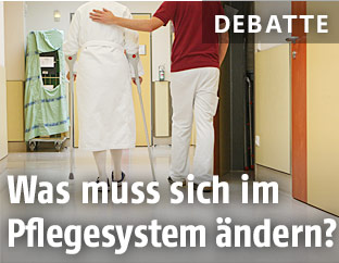 Eine Patientin geht mit einem Pfleger durch einen Gang