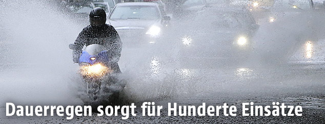 Motorradfahrer auf überfluteter Straße