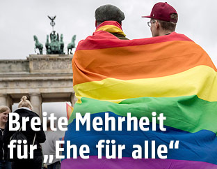 Pärchen mit Regenbogen-Fahne vor dem Brandburger Tor