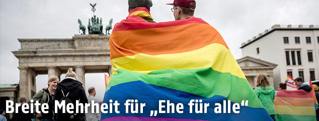 Pärchen mit Regenbogen-Fahne vor dem Brandburger Tor