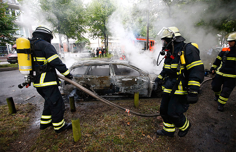 © Reuters/Hannibal Hanschke Polizisten löschen in Brand gestetztes Auto