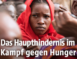 Frau aus dem Südsudan wartet mit anderen Menschen in einem Auffanglager auf humanitäre Hilfe
