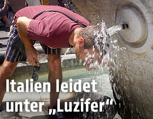 Mann kühlt sich unter einem Brunnen