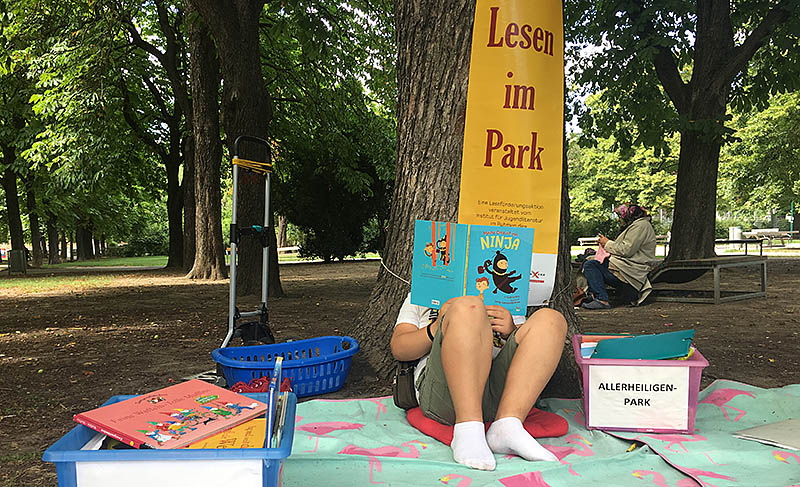 Ein Junge liest im Park ein Buch