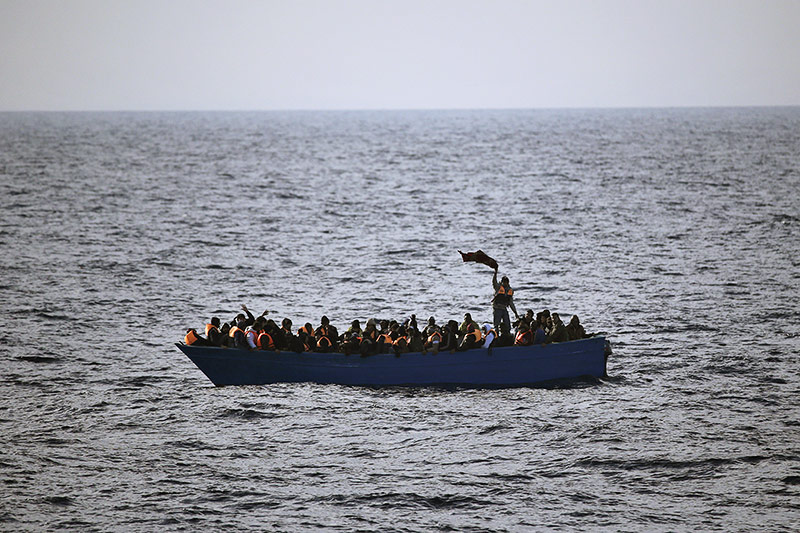 © APA/AP/Emilio Morenatti Menschen auf einem überfüllten Boot auf hoher See winken um Hilfe