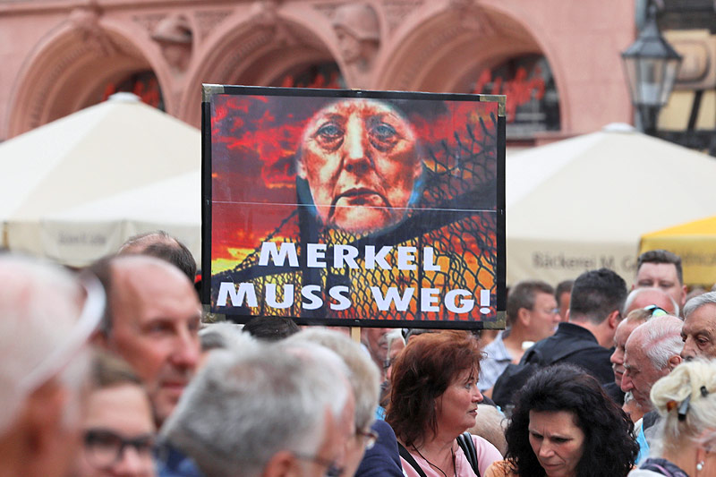 Demonstranten mit einem Schild mit der Aufschrift "Merkel muss weg"