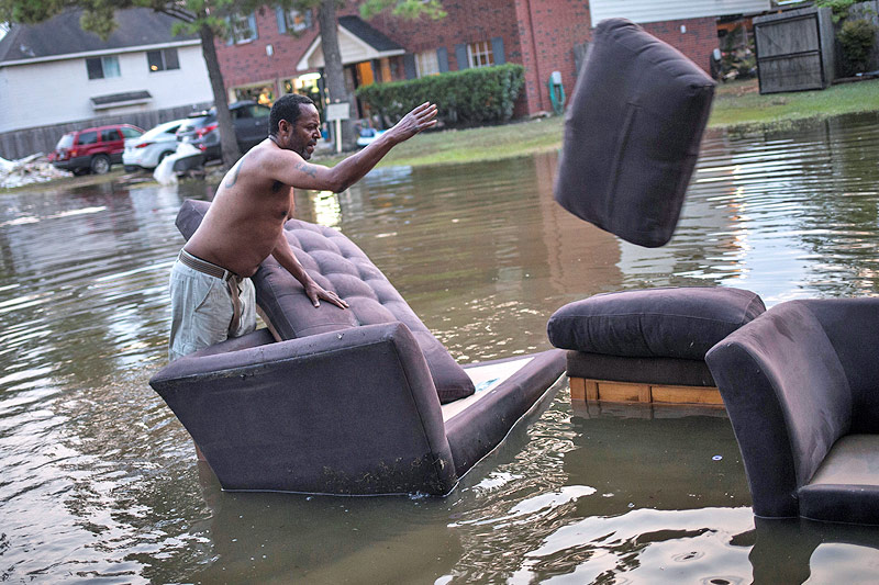 © Reuters/Adrees Latif Ein Mann wirft einen Polster von einem im Wasser stehenden Sofa