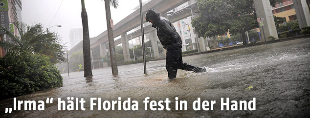 Ein Mann überquert im Regen eine überschwemmte Straße in Miami