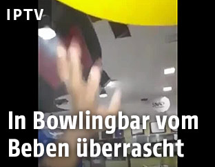 Ein Mann in einer Bowlingbar hält die Hand in die Höhe