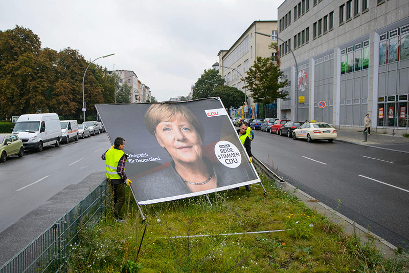 © APA/AP/dpa/Gregor Fischer Arbeiter entfernen Plakat mit Angela Merkel