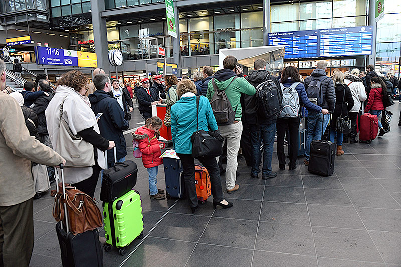 © APMaurizio Gambarini Menschen stehen in einem Bahnhof Schlange
