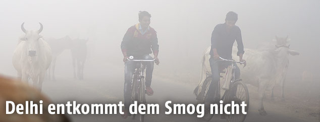 Zwei Radfahrer im Smog von Neu Delhi