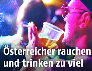 Mann mit Bier und Zigarette in der Hand