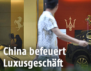 Ein Chinese geht an der Auslage eines Ferrari- und Maserati-Geschäfts vorbei