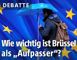 Mann mit Regenschirm vor EU-Logo