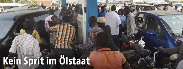 Menschen stehen bei einer Zapfs&auml;ule an