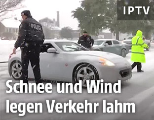Quergestelltes Auto auf Schneefahrbahn neben Polizisten