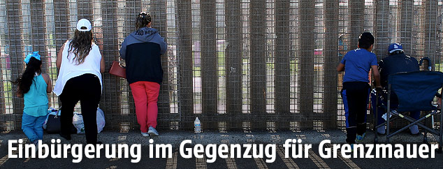 Mexikaner stehen vor einer Mauer an der US-Grenze
