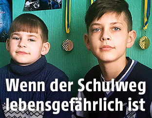 Zwei Buben in schulpflichtigem Alter sitzen auf einer Couch