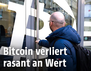 Mann betritt ein Gebäude mit Bitcoin-Werbung an der Tür