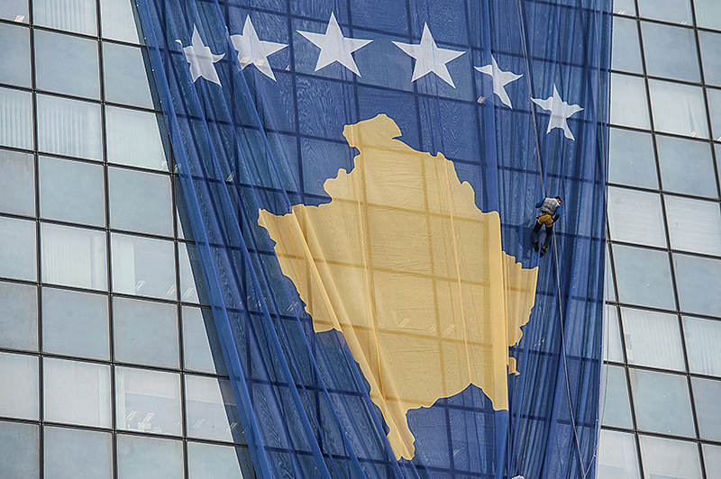 © APA/AFP/Armend Nimani Ein Arbeiter montiert eine große Kosovo-Flagge auf dem Regierungsgebäude in Pristina