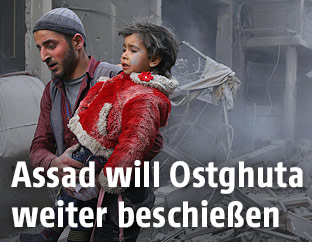 Ein Mann tr&auml;gt ein Kind durch Schutt