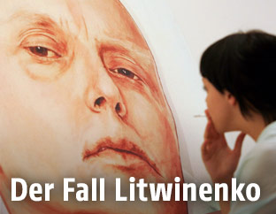 Frau blickt auf ein an eine Hauswand gemaltes Porträt des russischen Agenten Alexander Litwinenko