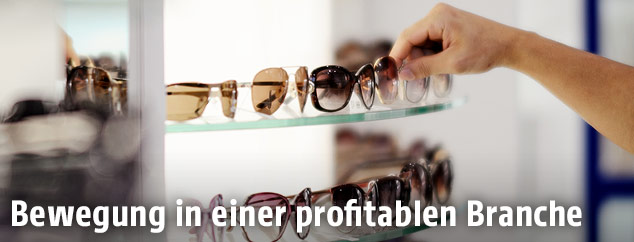 Jemand nimmt eine Sonnenbrille vom Regal