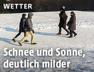 Menschen gehen im Schnee bei Sonnenschein spazieren