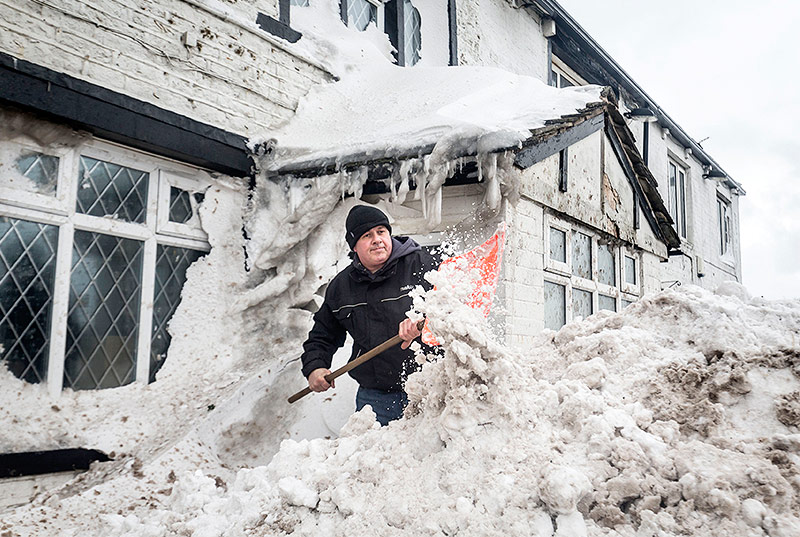 Mann schaufelt Schnee in Manchester