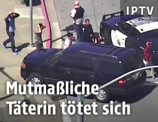 Personen mit Händen hinter dem Kopf gehen an Polizisten vorbei