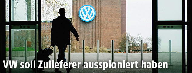 Ein Mann mit einem Trolley verlässt ein Gebäude gegenüber dem VW-Werk in Wolfsburg