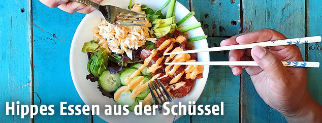 Zwei Hände mit Gabeln und eine Salatschüssel