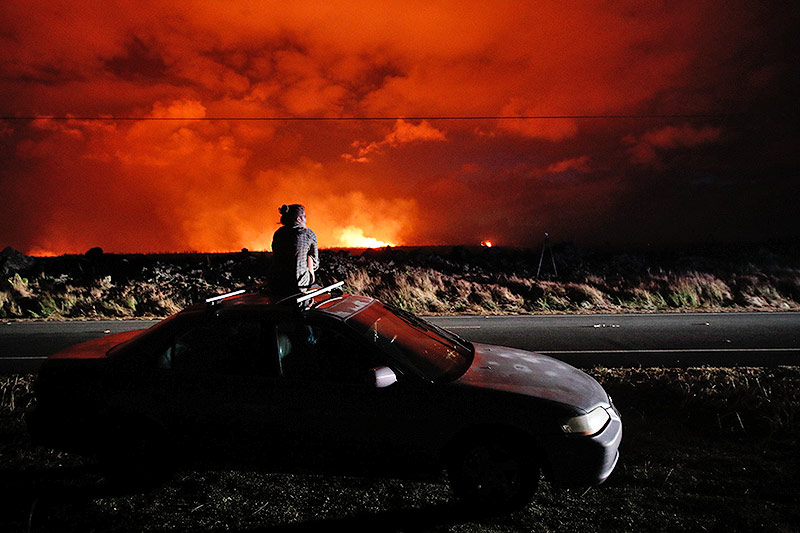 © AP/Jae C. Hong Eine Frau sitz auf einem Auto und beobachtet den Vulkan Kilauea