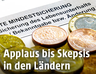 Münzen liegen auf einem Antrag auf Mindestsicherung