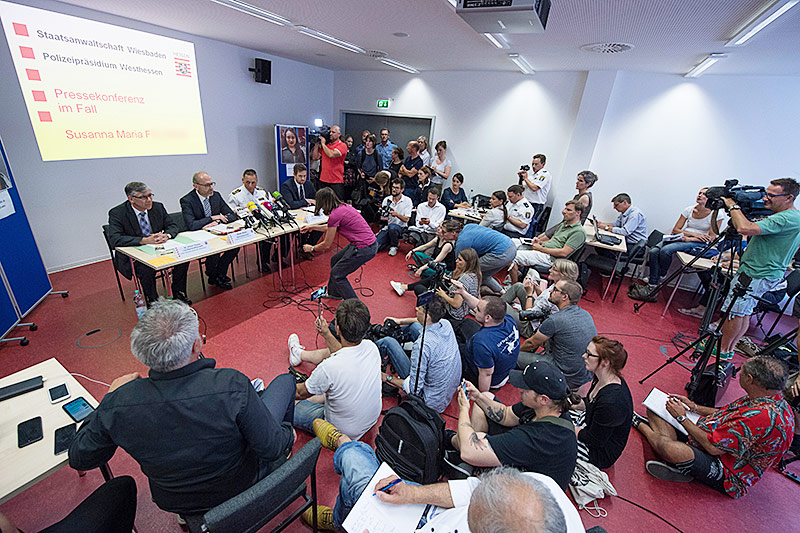 Journalisten fotografieren bei einer Pressekonferenz ein Foto des Verdächtigen