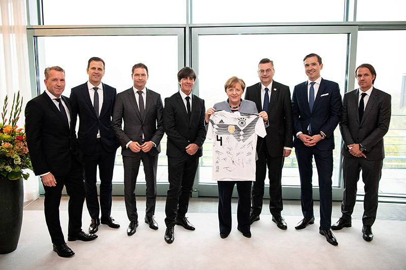 © picturedesk.com/Action Press/Bundesregierung Eine DFB-Delegation mit DFB-Präsident Reinhard Grindel und Bundestrainer Joachim Löw übergibt Bundeskanzlerin Angela Merkel ein WM-Trikot