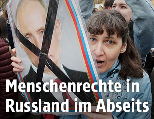 Demonstranten mit einem durchgestrichenen Putin-Plakat