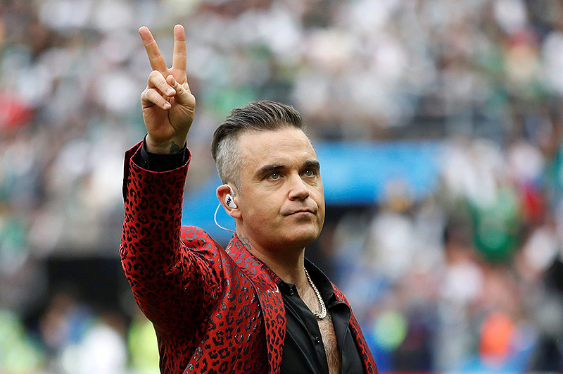 Robbie Williams macht mit zwei Fingern das Peace-Zeichen