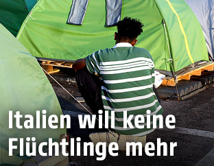 Ein Asylwerber sitzt zwischen Zelten