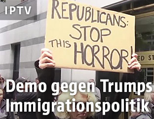 Demonstranten halten ein Schild gegen Trumps Politik ein die H&ouml;he