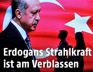 Passanten gehen an einem Bildschirm vorbei, auf dem Recep Tayyip Erdogan zu sehen ist