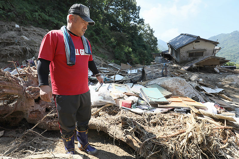 © APA/AFP/Jiji Press Mann blickt in Hiroshima auf sein durch eine Schlammlawine zerstörtes Haus