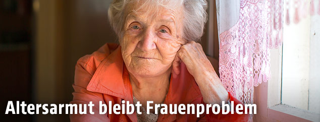 Eine ältere Frau sitzt an einem Tisch