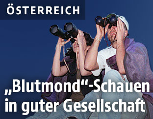 Ein junges Paar schaut mit Fernrohren in den Himmel