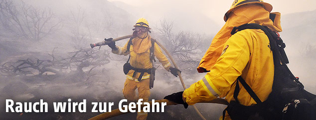 Feuerwehrleute mit Rauch im Hintergrund