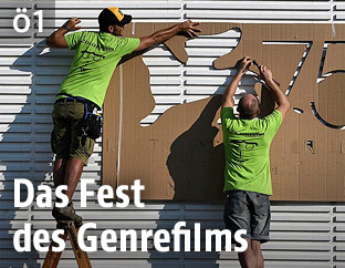 Arbeiter vor dem Logo des Filmfestivals in Venedig